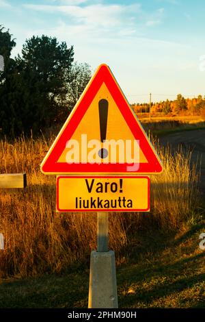 Un cartello, condizioni scivolose in lingua finlandese nel luogo di pulizia dei tappeti al tramonto . Segnalazione di condizioni scivolose. Foto Stock