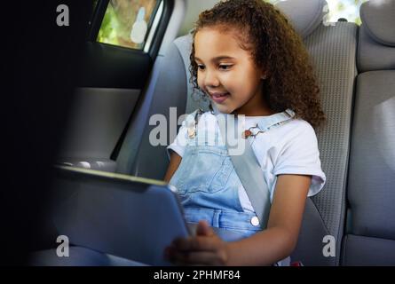 Bambino in auto, tablet e video durante il viaggio su strada con cintura di sicurezza e dispositivo per giocare a videogame online educativi. Tecnologia, navigazione in Internet e. Foto Stock