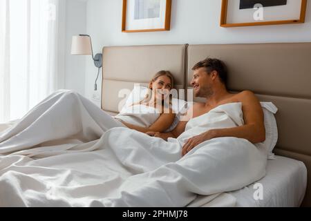 felice coppia è sdraiato in letto da camera e divertirsi insieme al mattino Foto Stock