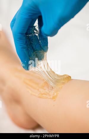 Processo di epilazione sulle gambe femminili. Sfondo bianco. Foto Stock