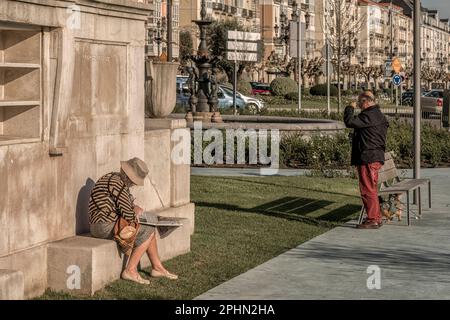 Donna anziana che legge il giornale seduto su una panchina presso la Fontana di Concha Espina nei Jardines de Pereda nella città di Santander, Cantabria. Foto Stock