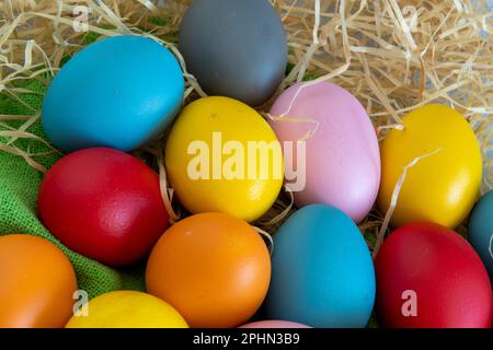 Uova dipinte in diversi colori per celebrare la Pasqua su uno sfondo di stoffa verde Foto Stock