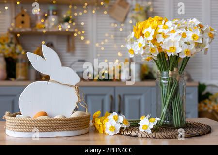 Sul tavolo si trova un cesto con un coniglio bianco di legno e uova naturali Foto Stock