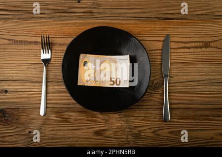 Denaro su piastra, concetto di spese alimentari, carta euro come cibo, mangiare denaro, pensione, borsa di studio, sovvenzione, Salario vivo, banconota da un piatto Vista dall'alto Foto Stock