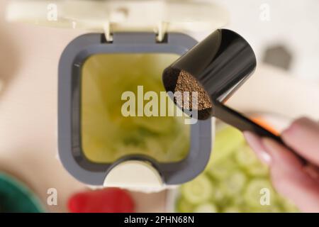 Persona che versa fermento bokashi in un contenitore di compost sul tavolo. Femmina che ricicla i residui organici dell'alimento in un bidone del composter con crusca di fermentazione a. Foto Stock