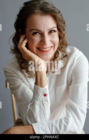 Ritratto di felice donna di mezza età in camicia bianca di cotone guardando la macchina fotografica Foto Stock