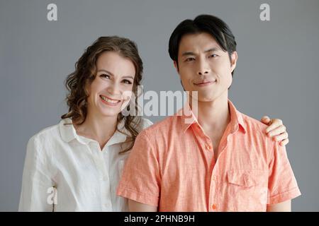 Ritratto di donna matura sorridente in piedi accanto al giovane asiatico e mettendo mano sulla spalla Foto Stock