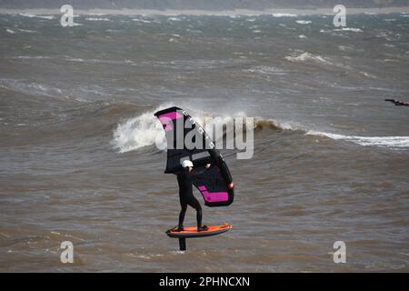 Un surfista alare scivola attraverso un mare mosso alimentato da una brezza rigida al largo della costa Jurrasic nella baia di Lyme. Dorset.UK Foto Stock