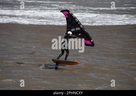 Un surfista alare scivola attraverso un mare mosso alimentato da una brezza rigida al largo della costa Jurrasic nella baia di Lyme. Dorset.UK Foto Stock