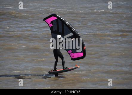 Un surfista alare scivola attraverso un mare mosso alimentato da una brezza rigida al largo della costa Jurrasic nella baia di Lyme. Dorset.UK Foto Stock