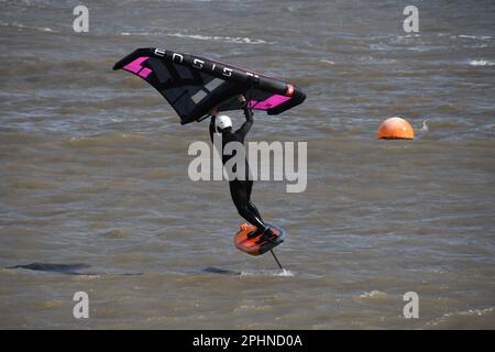 Un surfista alare scivola attraverso un mare mosso alimentato da una brezza rigida al largo della costa Jurrasic nella baia di Lyme. Dorset.UK Foto Stock