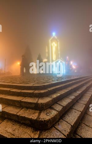 Antica chiesa in pietra di Sapa con cielo notturno nebbia. Destinazione di viaggio più popolare in Sapa, Laocai of Vietnam Foto Stock