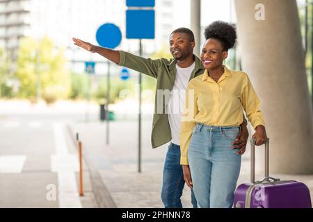 Allegri sposi africani con Travel Suitcase Hailing Taxi Cab all'aperto Foto Stock