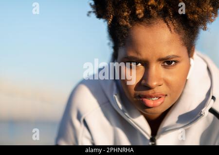 Ritratto di motivata giovane donna nera in Sportswear in posa all'aperto Foto Stock