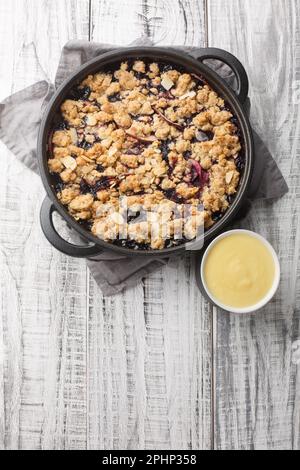 Torta Smulpaj svedese cotta con mele e mirtilli primo piano in una padella sul tavolo. Vista verticale dall'alto Foto Stock