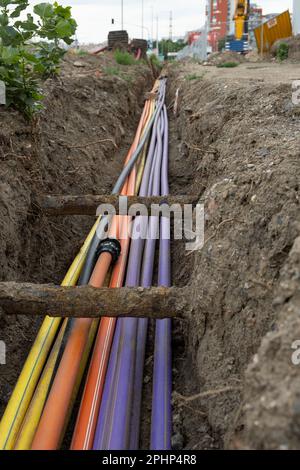 installazione di infrastrutture per cavi elettrici sotterranei. Cantiere con molti cavi di comunicazione protetti in tubi. elettrico e alta-spe Foto Stock