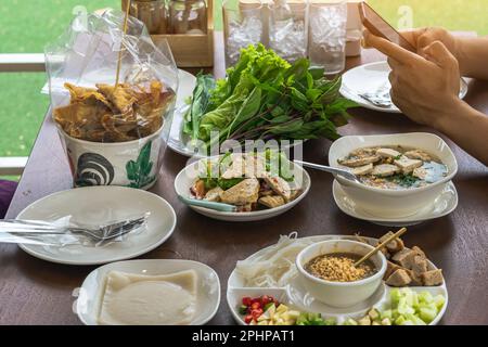 Insalata di salsiccia di maiale vietnamita piccante (Yum Moo Yor). Salsiccia di maiale insalata piccante tailandese e Vietnam cibo con altri piatti appetitosi e verdure sul bosco Foto Stock