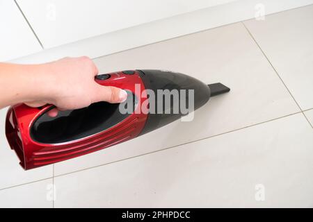 Aspirapolvere per auto rosso, tenendo in mano un aspirapolvere per auto, pulire il pavimento Foto Stock