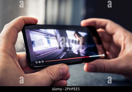 Riproduci film in streaming e guarda video con il telefono. Serie TV in servizio on-demand on-line VOD sullo schermo dello smartphone. Applicazione lettore multimediale mockup nel cellulare. Foto Stock