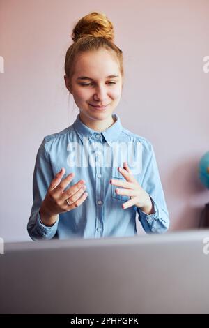 Giovane studentessa che ha classi, imparare online, guardare la lezione da remoto, ascoltare il professore, parlare con i compagni di classe in videochiamata da casa Foto Stock