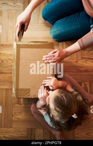 Donna che disimballa un pacco di cartone in camera a casa. Bambina in attesa di aprire un regalo in pacchetto Foto Stock