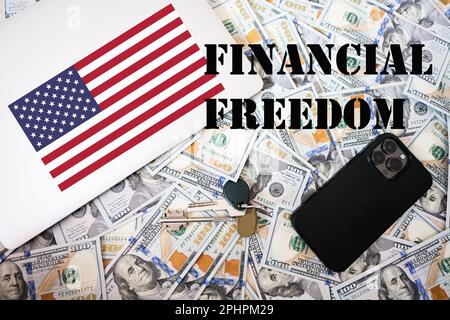 Concetto di libertà finanziaria. Bandiera degli Stati Uniti, denaro in dollari con chiavi, computer portatile e telefono sfondo. Foto Stock