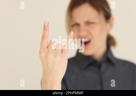 La donna che urla blurry mostra il gesto delle corna con le dita Foto Stock