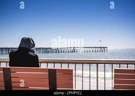 Vista posteriore di un uomo seduto vicino al molo di Ventura e guardandolo Foto Stock