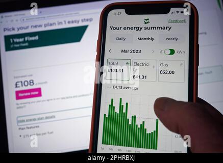 L'app OVO Energy su un telefono cellulare viene tenuta contro uno schermo di un computer portatile che visualizza i dettagli di una tariffa FISSA OVO Energy di un anno per i clienti, in quanto il fornitore ha offerto la sua prima offerta al di sotto del limite del £2.500 del governo sulle bollette tipiche delle famiglie in calo dei prezzi all'ingrosso del gas. Il gigante dell'energia offre ai clienti esistenti una tariffa fissa di un anno pari a £2.275 dollari, con una sottoquotazione della garanzia del prezzo dell'energia (EPG) del governo. Data immagine: Domenica 26 marzo 2023. Foto Stock