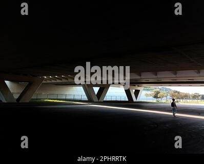 Un uomo solitario in una città moderna sotto un ponte sul cavalcavia Foto Stock