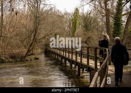 Wherwell, Hampshire, Inghilterra, Regno Unito. 2023. Due donne fanno una passeggiata invernale attraverso il famoso River Test a Wherwell. Famoso per la pesca alla trota. Foto Stock