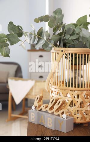 Cesto di vimini con bellissimi rami di eucalipto e frase Ciao Baby su tavolo di legno all'interno. Design degli interni Foto Stock