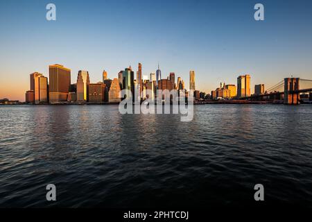 Brooklyn, NY - USA - 26 marzo 2023 Vista panoramica orizzontale all'alba del quartiere finanziario di Manhattan visto attraverso l'East River da Brooklyn Bridg Foto Stock