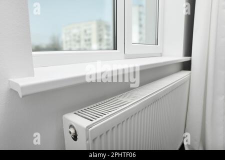 Moderno radiatore sotto la finestra a casa. Riscaldamento centralizzato Foto Stock