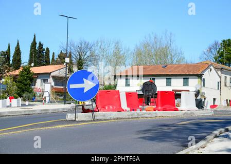 Strada con segnaletica stradale a senso unico traffico, barriera di sicurezza in plastica e segnaletica gialla temporanea nelle giornate di sole. Lavori di costruzione Foto Stock