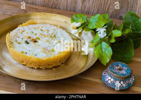 Ghewar o ghevar è un dolce tradizionale di rajasthan. È fatto di latte, farina, ghee e zucchero. Frutta secca e panna malai in cima. E' servito in br Foto Stock