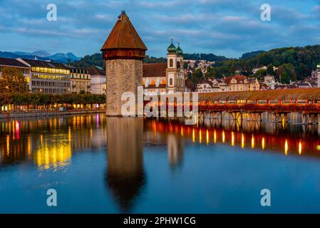 Vista notturna di Kapellbruecke con la chiesa di Francesco Saverio nella città svizzera di Lucerna. Foto Stock