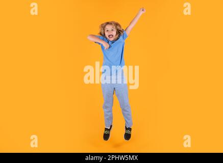 Foto a tutta lunghezza di Kid Boy Jump High Wear camicia casual a scacchi isolata su sfondo giallo. Ritratto del ragazzo che salta. Bambino che salta, divertendosi Foto Stock