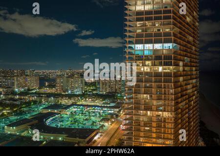 Vista aerea dell'alto grattacielo residenziale di notte nella città di Sunny Isles Beach in Florida, Stati Uniti. Sviluppo di alloggi nella moderna area urbana americana Foto Stock