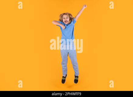 Foto a tutta lunghezza di Kid Boy Jump High Wear camicia casual a scacchi isolata su sfondo giallo. Ritratto del ragazzo che salta. Bambino che salta, divertendosi. Foto Stock
