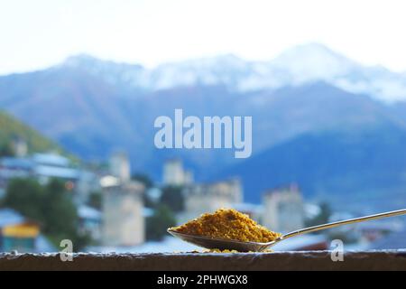 Primo piano un cucchiaio di Georgian Svan sale con sfocata montagne del Caucaso e Mestia città nel contesto Foto Stock