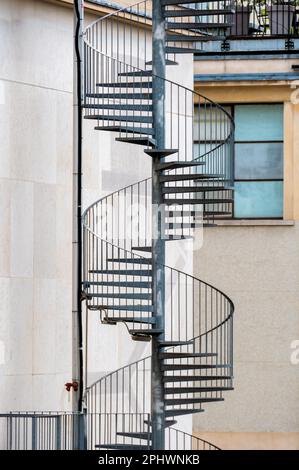 Scala esterna di fuga a spirale metallica che conduce alle uscite di emergenza sul retro di un edificio Foto Stock