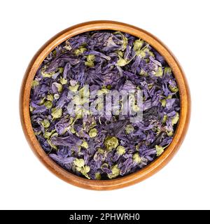 Fiori di mallow viola secco, in una ciotola di legno. Teste di fiori di Malva sylvestris, conosciuto anche come mallow comune, usato per il tè alle erbe. Foto Stock