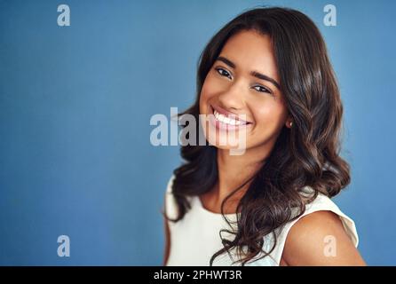 Tutto ciò che riguarda la fiducia. Ritratto di studio di una giovane donna fiduciosa che si posa su uno sfondo blu. Foto Stock