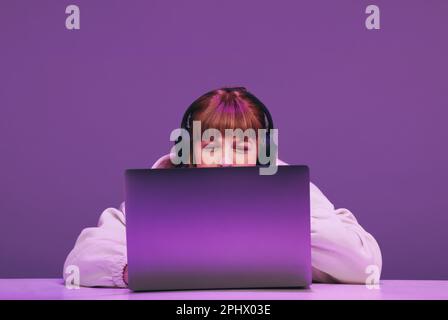 Donna che guarda premurosa mentre gioca un videogioco online sul suo laptop. Giocatore femminile che utilizza un servizio di streaming interattivo in uno studio. Foto Stock