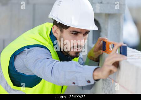 L'uomo muratore è livello di misurazione Foto Stock