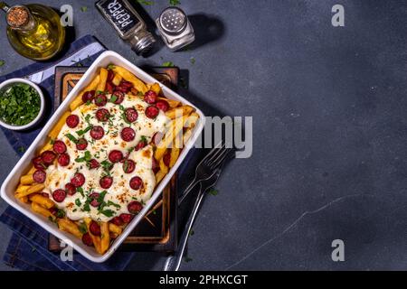 Patatine fritte caricate con la pizza. Pepperoni fatti in casa e formaggio Pizza French Fries. Patatine fritte al forno casseruola di patate con formaggio, peperoni salame e Foto Stock