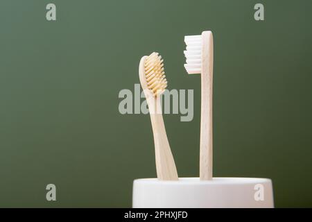 Due spazzolini di bambù in vetro bianco su sfondo verde. Il concetto di sostenibilità e il rifiuto della plastica. Il concetto di hygi Foto Stock