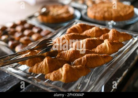 Un angolo alto di croissant appena sfornati posti sul vassoio in buffet per la prima colazione Foto Stock