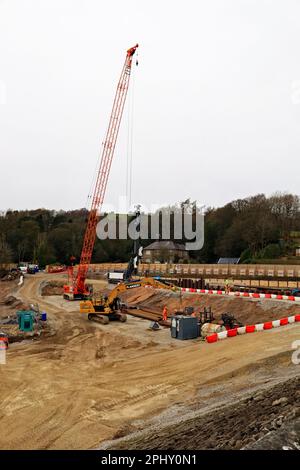 Vista dalla passeggiata sulla cima della diga di Toddbrook giù mentre la grande gru sta installando il riempimento per il nuovo canale di fuoriuscita nelle riparazioni alla diga Foto Stock